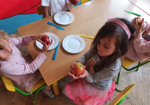 Dziewczynka pokazuje złożone jabłko z części.